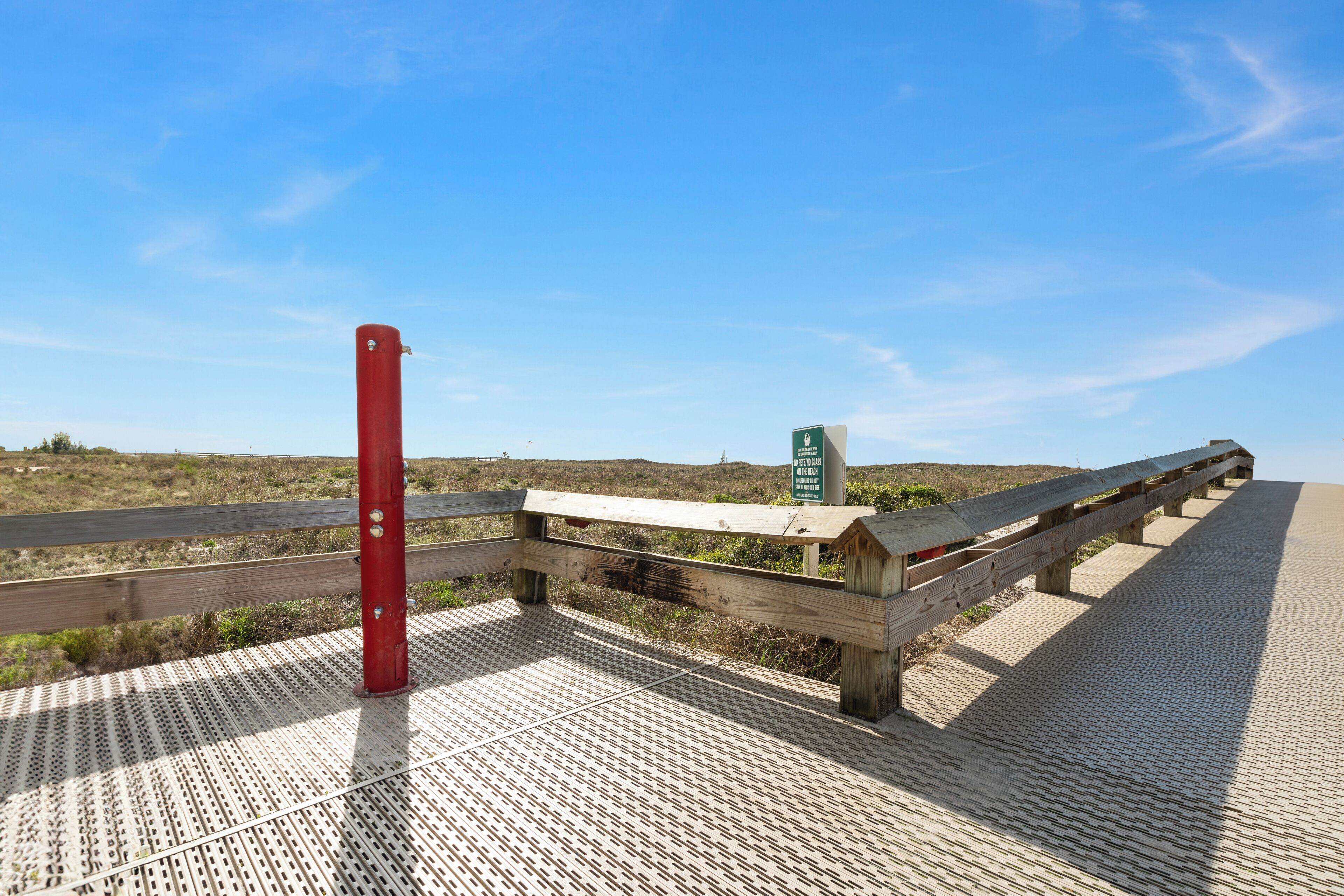 Une promenade en bois avec un poteau rouge et un panneau vert.