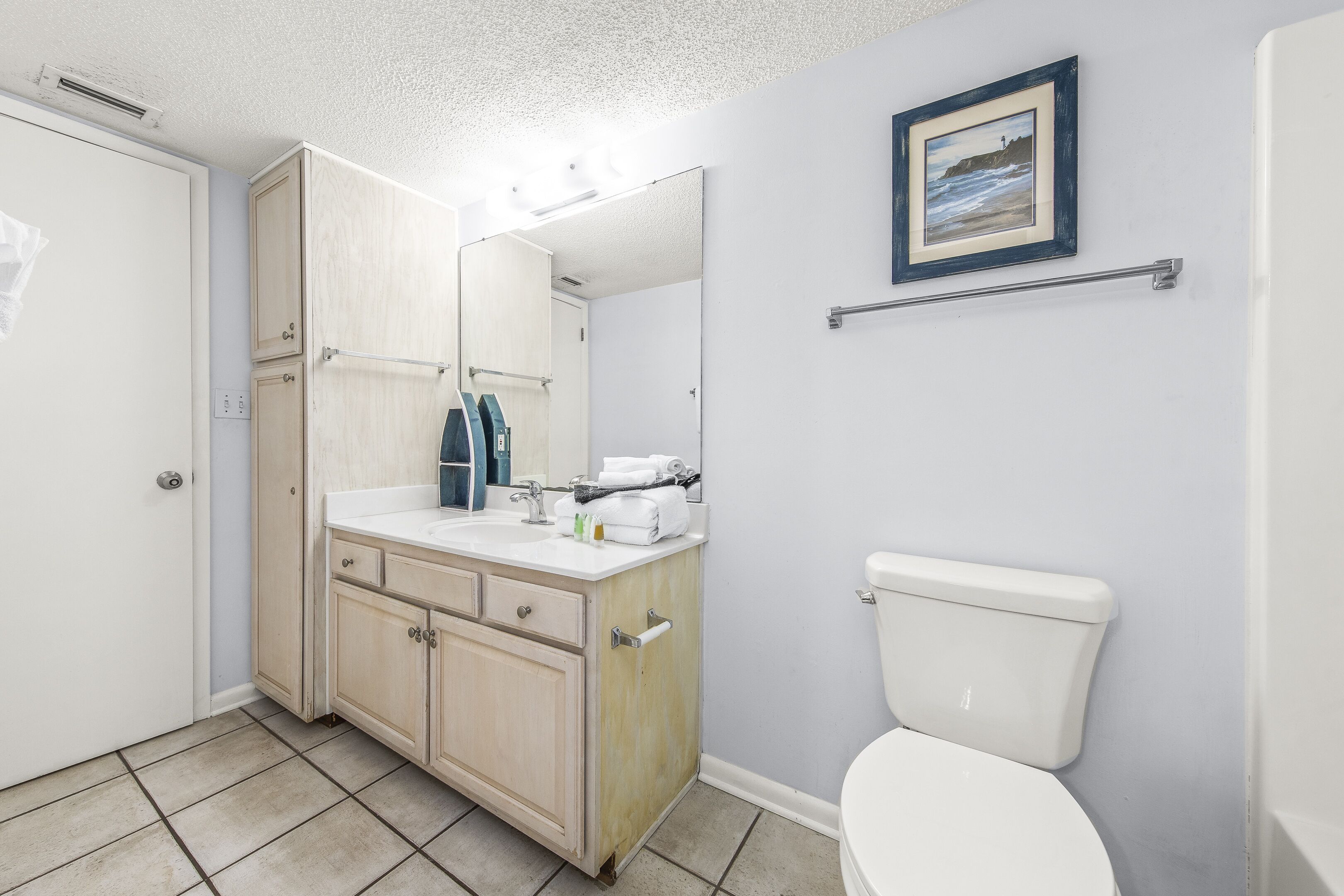 A bathroom with a toilet, sink, and cabinet.
