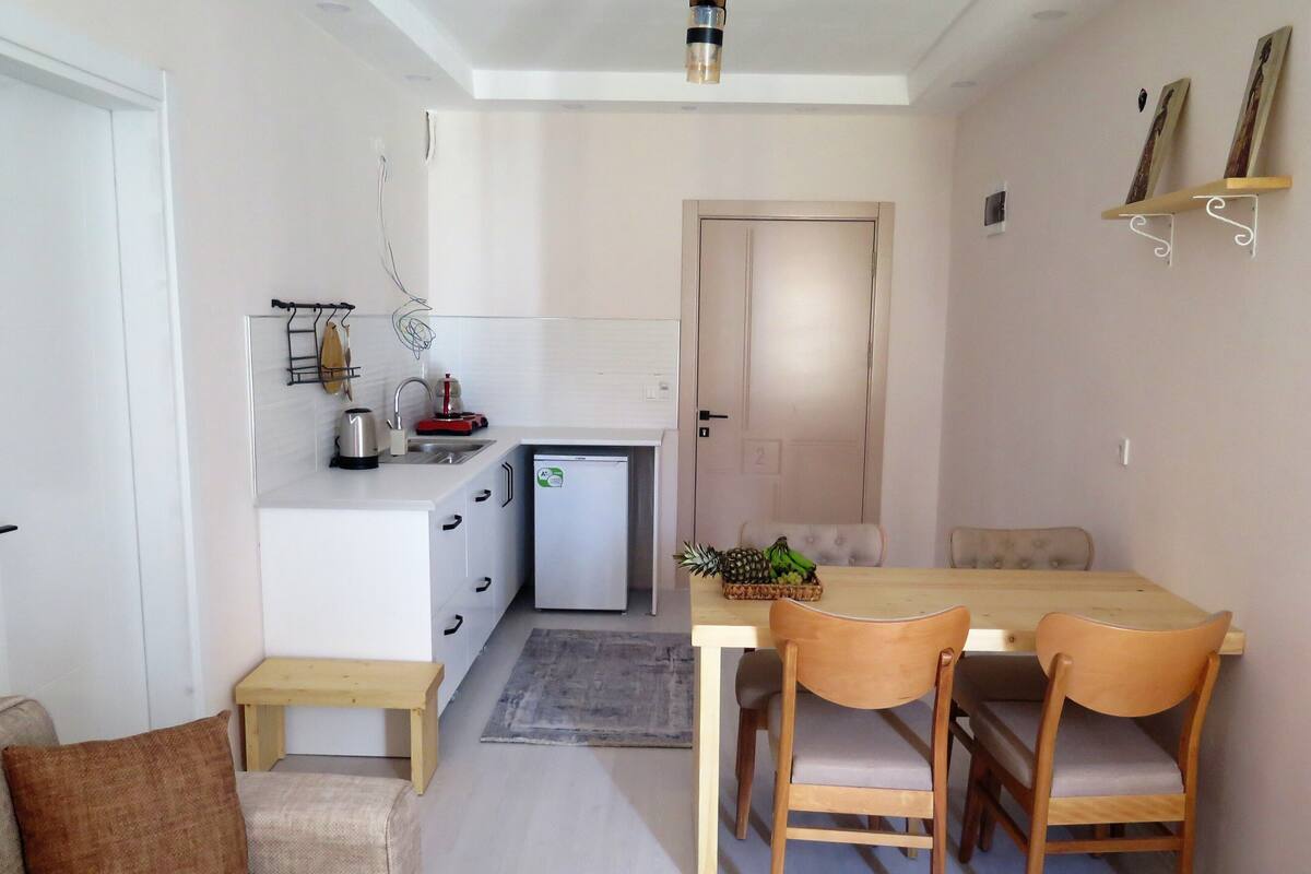 A compact living space with a kitchenette, a dining area with a table and chairs, and a sofa.