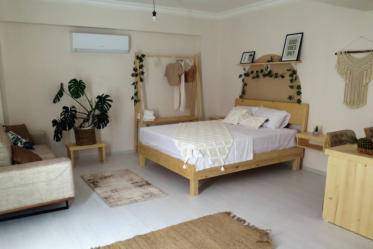 A bedroom with a wooden bed, a bedside table, a hanging plant, and a macrame wall hanging.