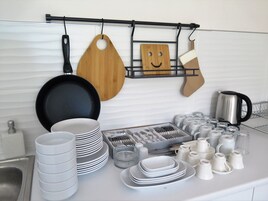 Una cocina con cubierta blanca, un lavamanos y diversos utensilios y utensilios de cocina ordenados.