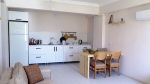 A modern kitchen with white cabinets, a dining table with chairs, and a small island. - Santa Center Pansiyon  (Demre)