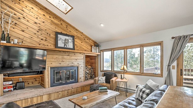 A cozy living room with a fireplace, a large TV, and a comfortable seating area. - Sunny Alpine Escape w/ Hot Tub + Mountain Vistas! (Fraser)