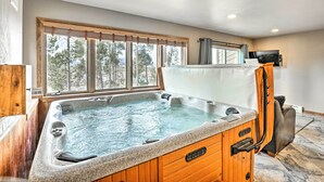 A hot tub in a room with a large window, wooden walls, and a television on the wall. - Sunny Alpine Escape w/ Hot Tub + Mountain Vistas! (Fraser)
