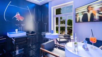 Ein moderner Barbereich mit Aquarium, Barhocker, Fernsehbildschirm und einem Cocktail auf dem Tisch.