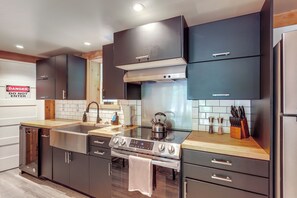 Una cucina moderna con mobili scuri, elettrodomestici in acciaio inossidabile e una parete di fondo rivestita di piastrelle.