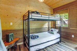 Un letto a castello con una radio, una finestra vista alberi e un pavimento in legno.