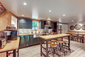 Une cuisine moderne dotée d’un îlot central, de tabourets de bar et d’appareils électroménagers en acier inoxydable.