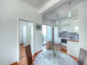 Una cocina moderna con armarios blancos, encimera de mármol e iluminación colgante.