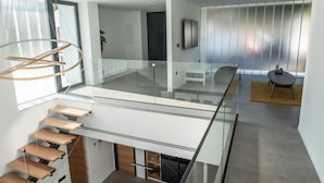 Et moderne interiør med en glas trappe, et fladskærms-tv og et minimalistisk design.