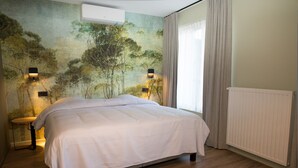 A bedroom with a bed, a mural on the wall, a radiator, and a window with curtains. - Appart Hotel En Ville - Studio 2 persons in the center of Bastogne (Bastogne)