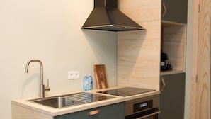 A compact kitchen with a built-in stove, oven, and a modern range hood. - Appart Hotel En Ville - Studio 2 persons in the center of Bastogne (Bastogne)