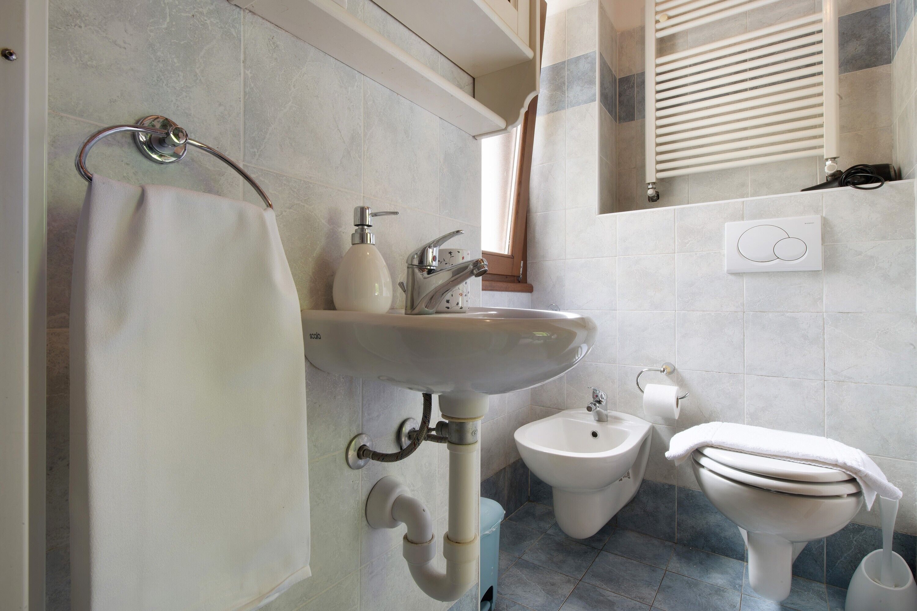 Ein Badezimmer mit Waschbecken, Bidet, Toilette und Handtuchhalter.