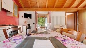 Techo de madera, una mesa de comedor con mantel floral, sillas, una botella de vino y copas de vino.
