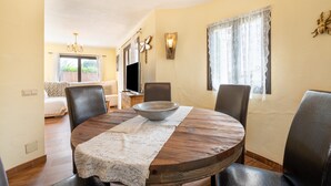 Un comedor con una mesa redonda de madera, cuatro sillas, un bol y un camino de mesa decorativo.