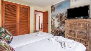 Une chambre d’hôtel équipée d’un lit, d’une télévision, d’une armoire et d’un mur décoratif.