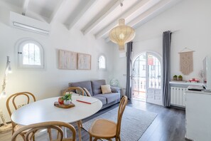 Ein modernes Wohnzimmer mit Esstisch, Sofa und Sesseln, einer Hängeleuchte und Blick durch eine Glastür.
