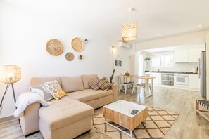 Ein modernes Wohnzimmer mit Sofa, Couchtisch und einem Essbereich mit Tisch und Stühlen.