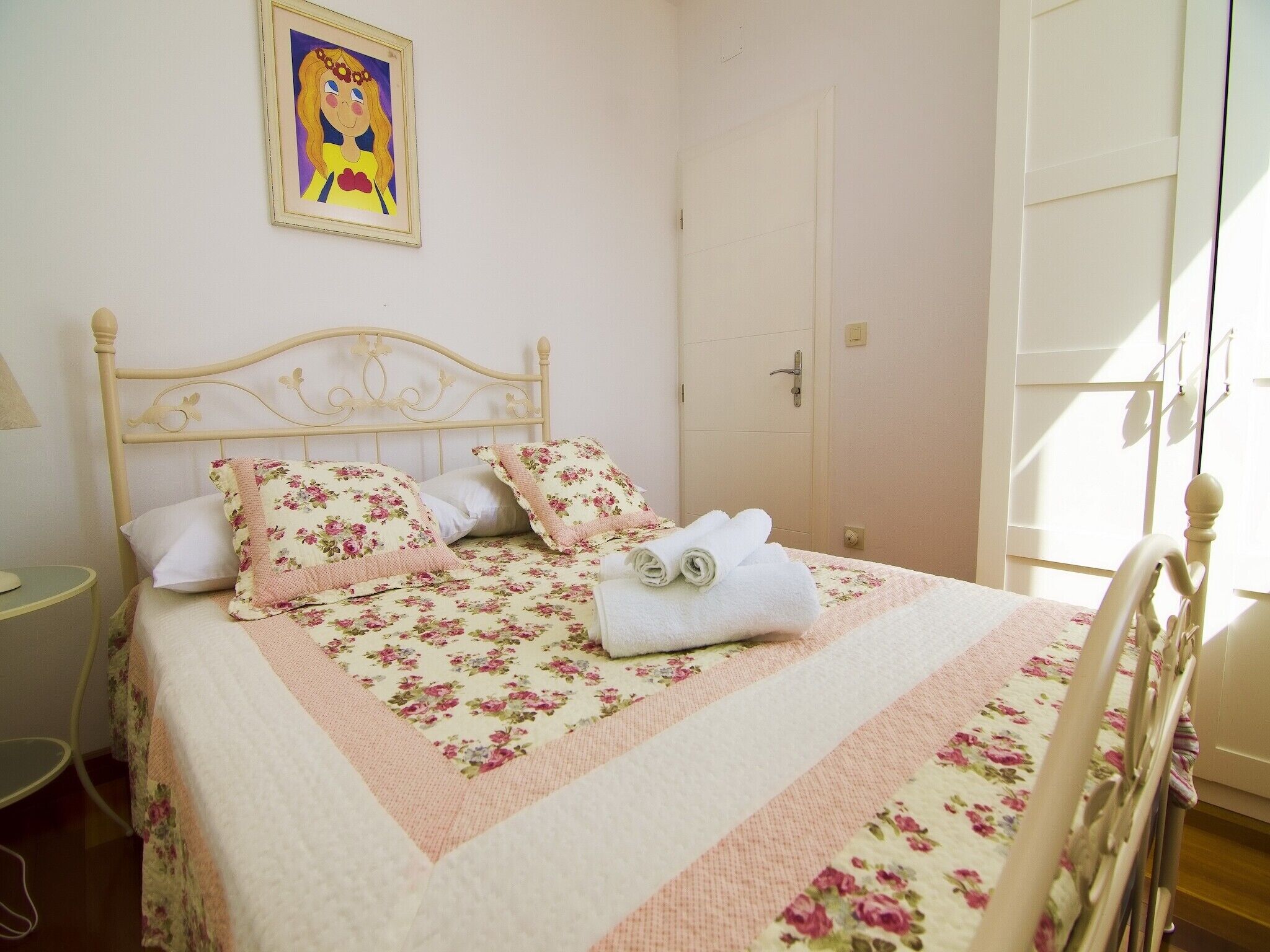 A neatly made bed with floral bedding and a white headboard.