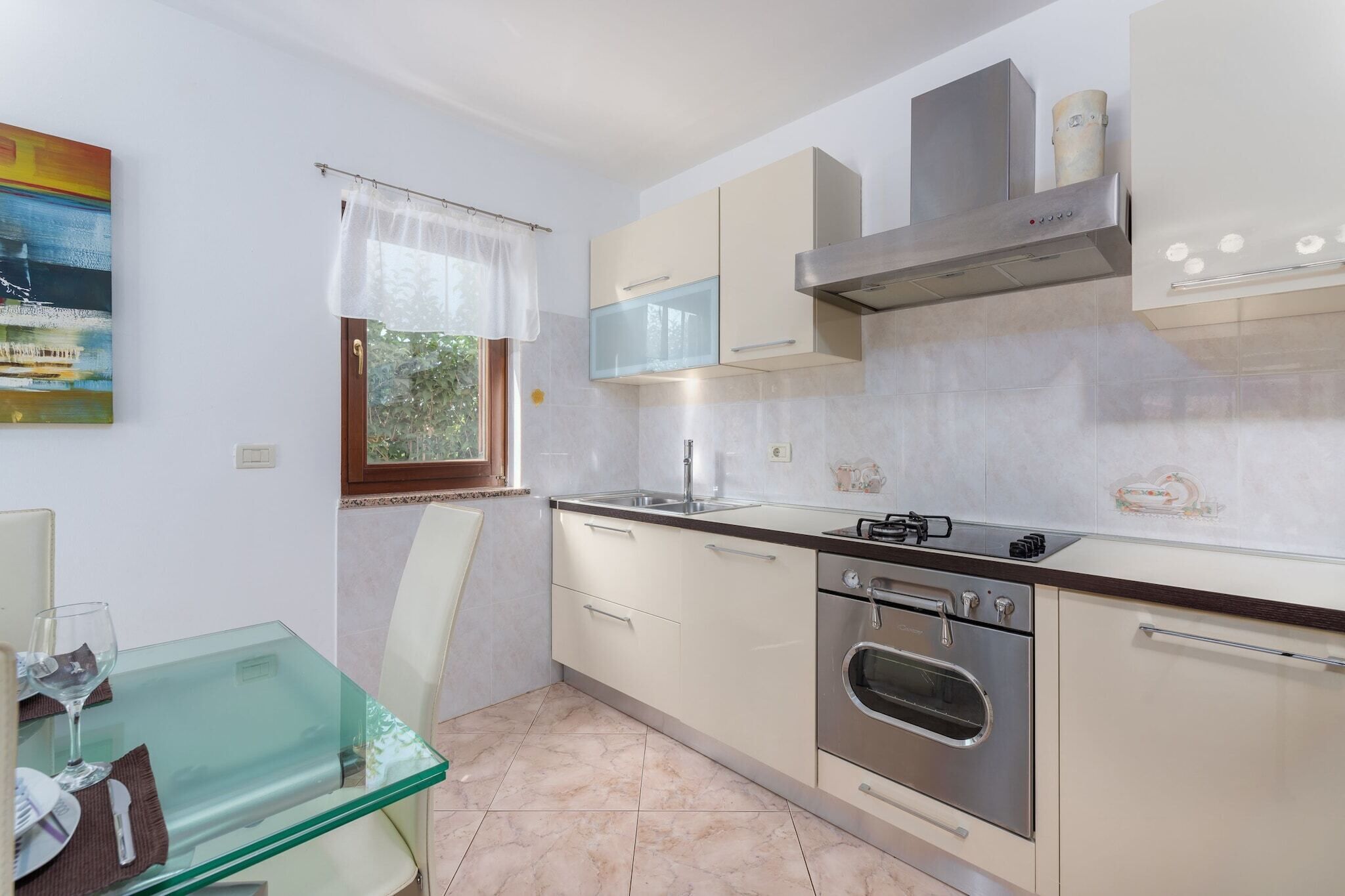 Una cocina moderna con una mesa de comedor de vidrio, electrodomésticos de acero inoxidable y una ventana con vistas.