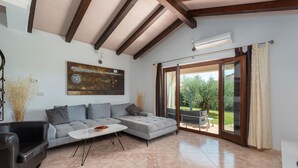 Una sala moderna con un sofá seccional gris, una mesa de centro blanca y un ventanal con vistas a zonas verdes.