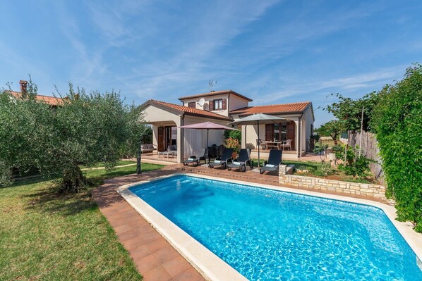 Il s’agit d’une propriété résidentielle dotée d’une piscine, d’un espace extérieur aménagé pour se détendre et d’un jardin bien entretenu.