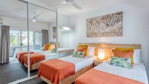 A hotel room with two beds, a large mirror, and a balcony with a view.
