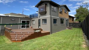 Une maison moderne à deux étages, dotée d’un patio couvert, d’une petite terrasse et d’un jardin clôturé.