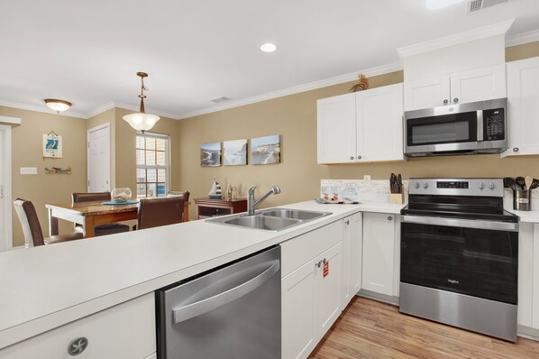 A modern kitchen with white cabinetry, stainless steel appliances, and a central island with a dishwasher.