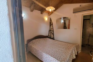 A bedroom with a bed, a hanging plant, a ceiling light, and a bathroom door. - Holiday Home Sisan near Beach & Pool (Sisan)