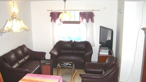 Ein Wohnzimmer mit zwei Ledersofas, einem kleinen Tisch, einem Fernseher und einer Lampe.