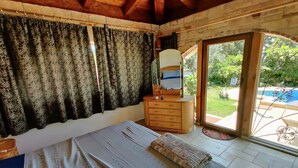 Ein Schlafzimmer mit Bett, Schminktisch, Spiegel und Blick ins Freie.