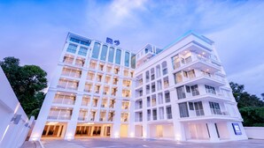Un hôtel à plusieurs étages doté d’une architecture moderne, avec des balcons et de grandes fenêtres.