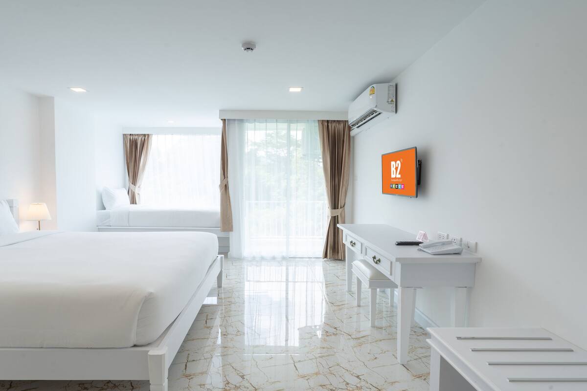 A hotel room with a bed, a desk, and a mounted TV displaying 'B2'.