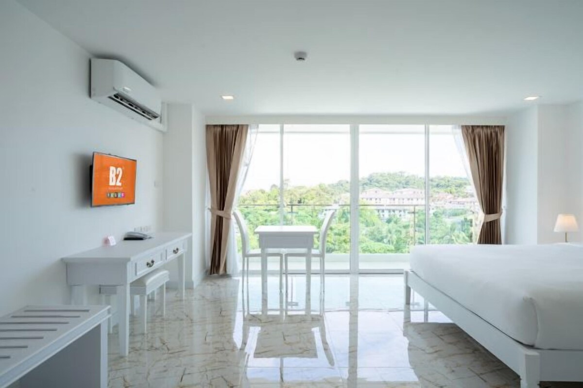 Una habitació d'hotel amb un llit, una taula de treball, una cadira i una televisió.