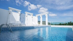A pool area with white columns, a tiled deck, and lounge chairs. - B2 Phuket Premier Hotel (Kathu)