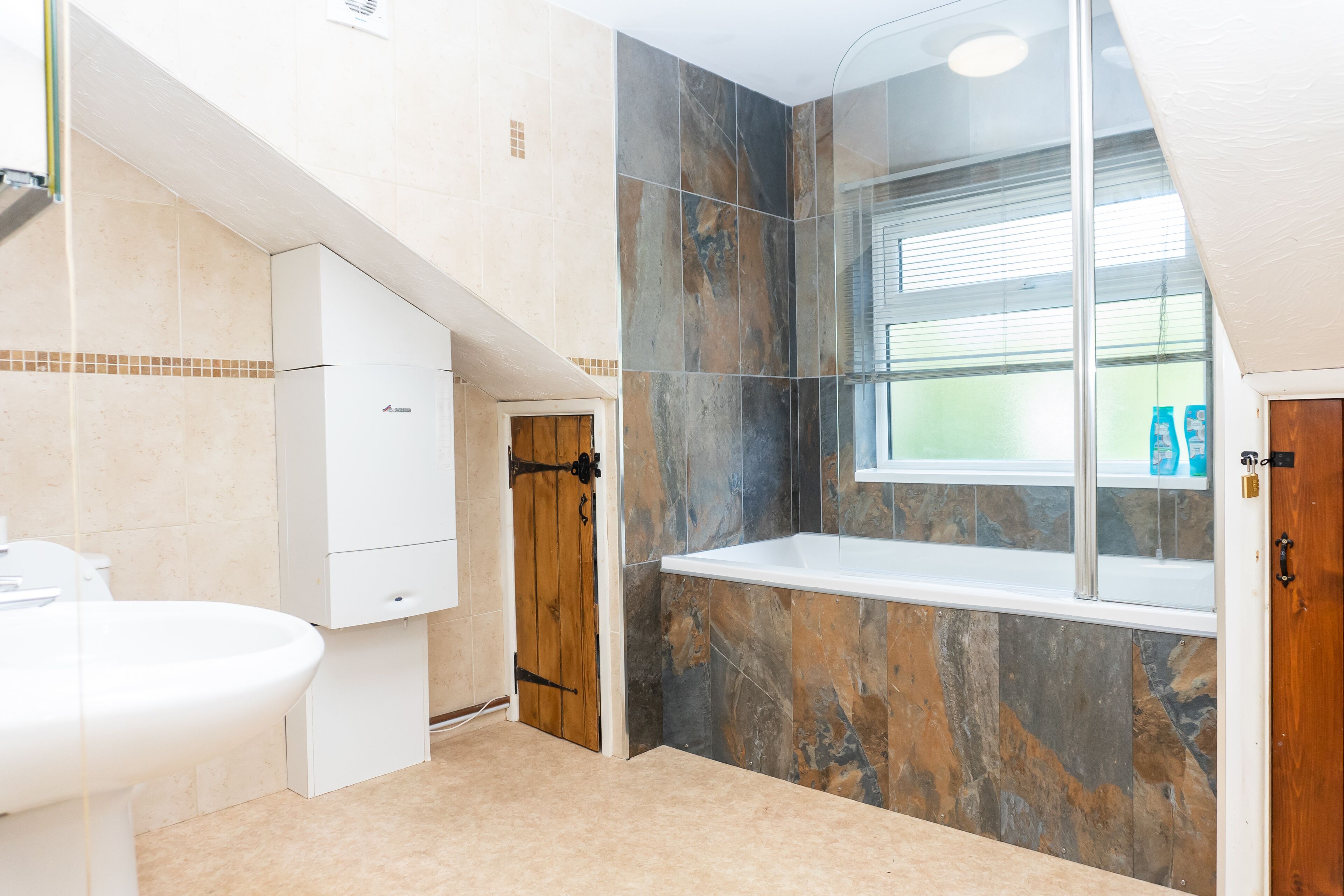 A bathroom with a toilet, a sink, a shower, and a window.