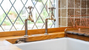 A kitchen sink with two faucets and a copper wire rack. - 2 Pound cottage (Gloucester)