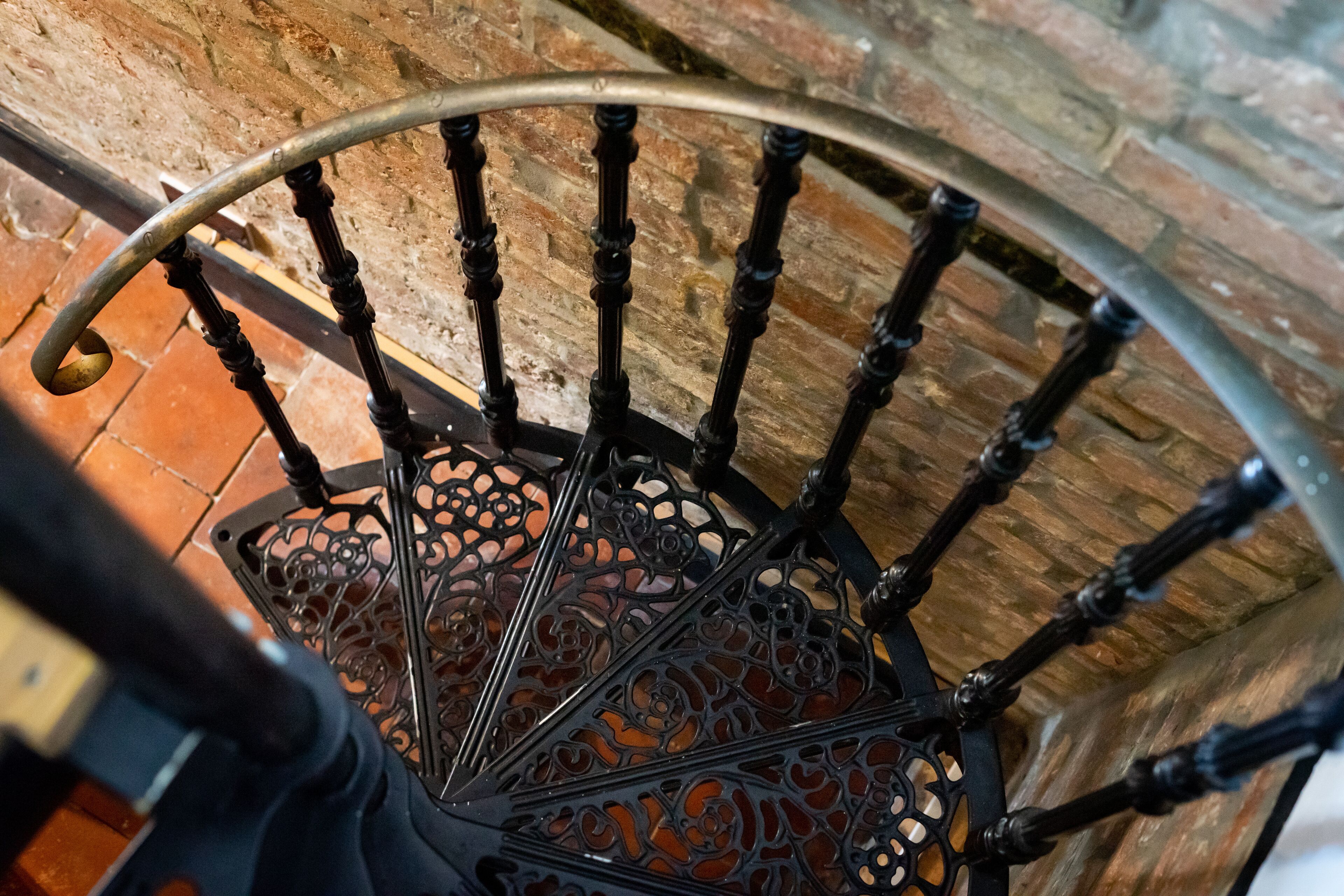 Gradi d'espiral amb barana metàl·lica ornamentada i un paviment amb dibuixos.