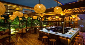 An outdoor bar area with wooden flooring, round tables, and hanging spherical lights. - Parque Mexico Boutique Hotel (Mexico City)