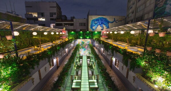 A rooftop garden with a mural of a blue panther, potted plants, and a glass walkway. - Parque Mexico Boutique Hotel (Mexico City)