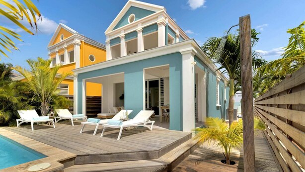 Un resort con piscina, lettini e un pontile di legno.