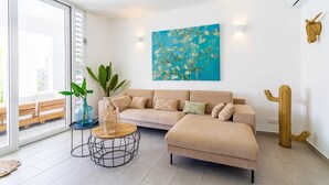 Un soggiorno moderno con un divano componibile beige, un tavolino rotondo e un grande quadro astratto appeso alla parete.