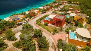 Un complejo turístico frente al mar con varias edificaciones, una piscina y vistas al océano.