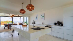 Una cocina moderna con una isla central, luces colgantes y una obra de arte en la pared.
