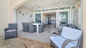 A spacious patio with wicker furniture, ceiling fans, and a view into the house. - Port Bonaire Reef A601 with stunning sea views, a peaceful setting and everything on one level (Kralendijk)