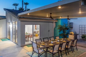 An outdoor dining area with a table set for six, surrounded by chairs.