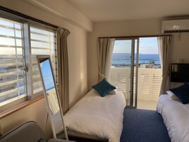 Una habitación de hotel con dos camas, televisión y balcón con vistas al mar.
