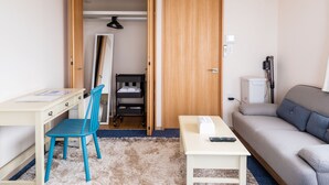 A compact room with a desk, chair, sofa, and a wardrobe. - Crystal Court (Miyakojima)