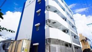A hotel with a blue and white facade, multiple balconies, and a clear sky. - Crystal Court (Miyakojima)
